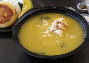 Ajiaco servido en un plato de barro con comidas colombianas